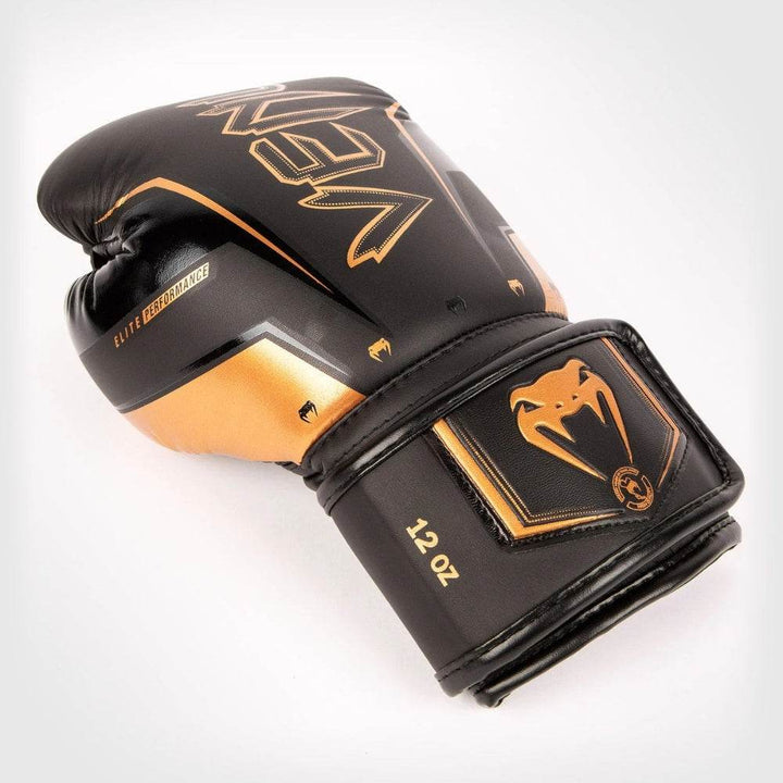 Black-bronze glove laid on side, emphasising bronze “VENUM” text across knuckles.
