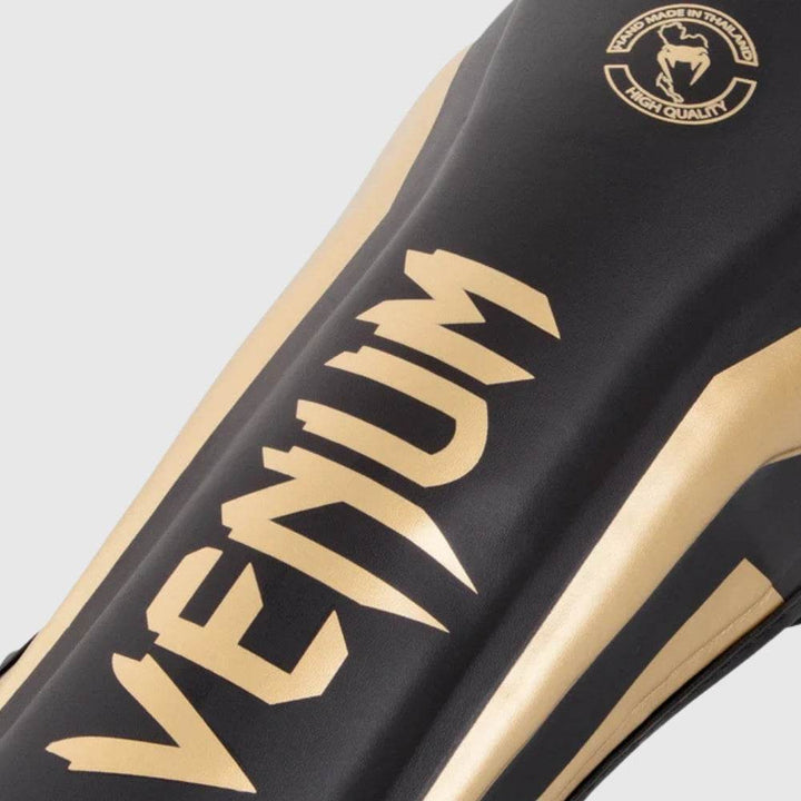 Close-up of black and gold elite stand up shinguard's Venum branding on shin panel.