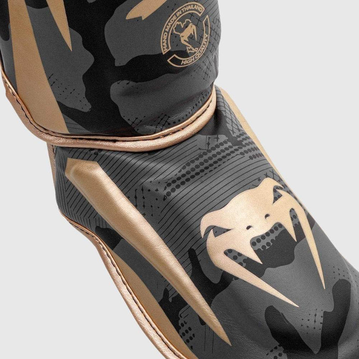 Detailed view of the foot protector, featuring the iconic Venum snakehead logo in gold and reinforced stitching.
