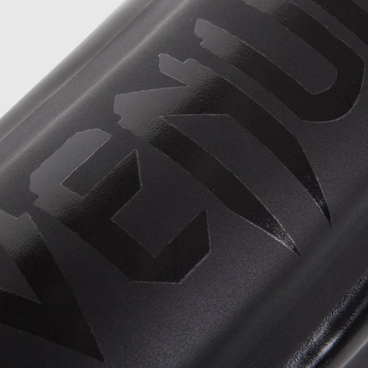 Close-up of black Venum logo printed on glossy synthetic leather.