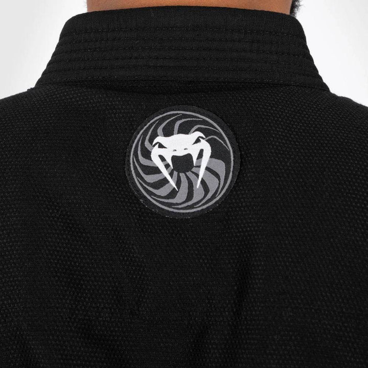 Close-up of the back collar area of the gi, highlighting the circular black-and-white Venum logo patch with a swirling design.