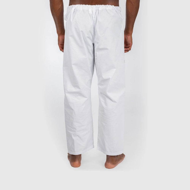 Close-up of the back side of the gi pants, showing the loose, straight fit and elastic waistband, with the model shirtless.