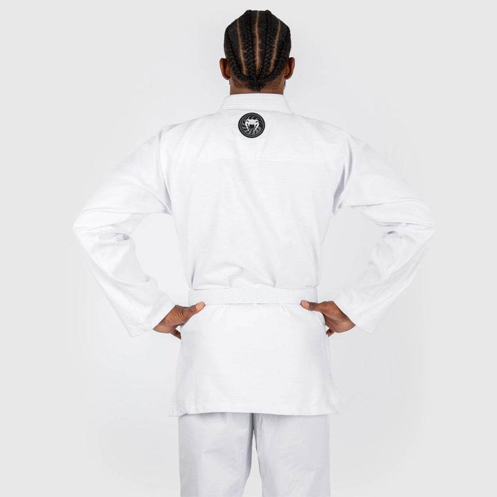 The model is shown from behind, highlighting the Venum circular logo patch centered on the upper back of the white gi jacket.