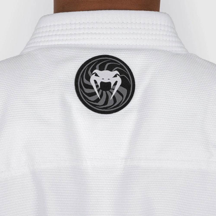 Close-up image of the circular Venum snakehead logo patch stitched to the upper back of the gi jacket.