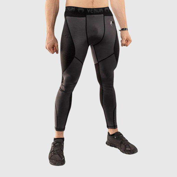 Front view of a male model wearing Venum men’s compression spats in black and grey, standing with feet apart.