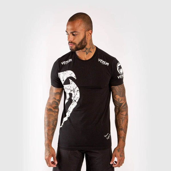 Man wearing a black Venum t-shirt with a large Venum white snake logo on the chest and "VENUM" branding on the collar and shoulders.