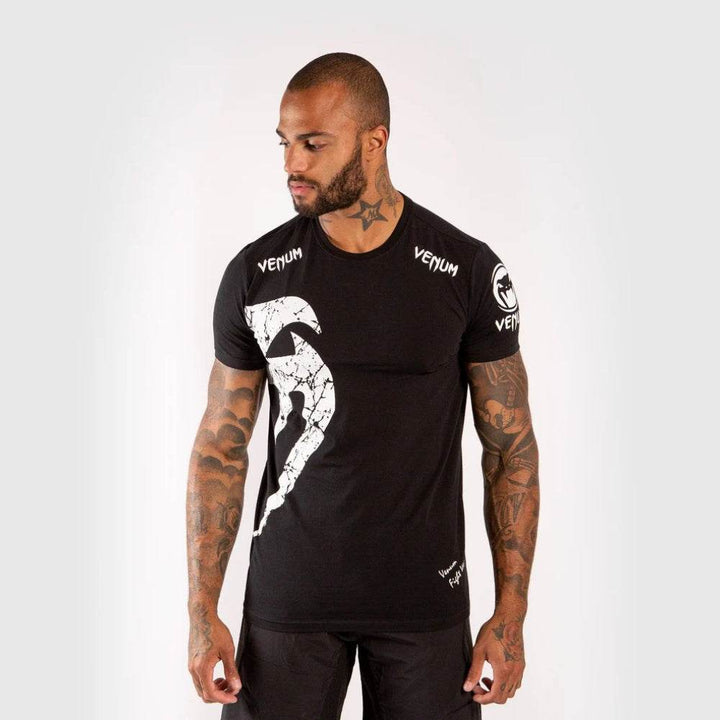 Man wearing a black Venum t-shirt with a large Venum white snake logo on the chest and "VENUM" branding on the collar and shoulders.