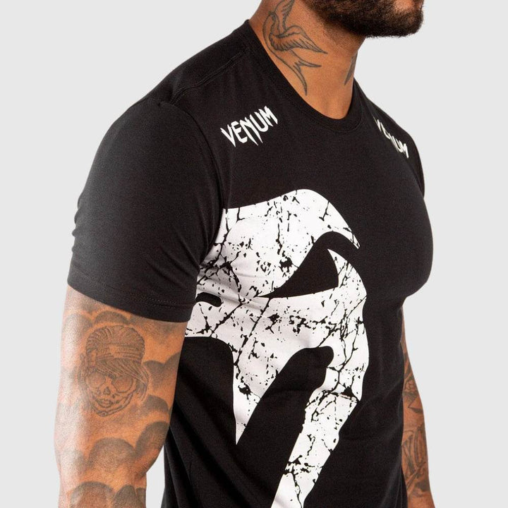 Detail of white Venum snake logo and "VENUM" print on the upper chest and shoulder.