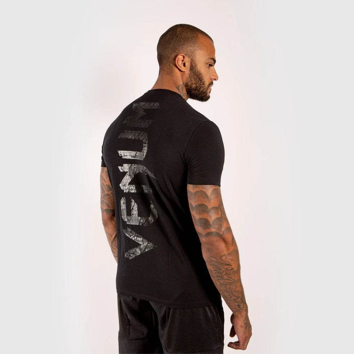 Angled rear-side view of the t-shirt highlighting the full vertical “VENUM” back print in gloss texture.
