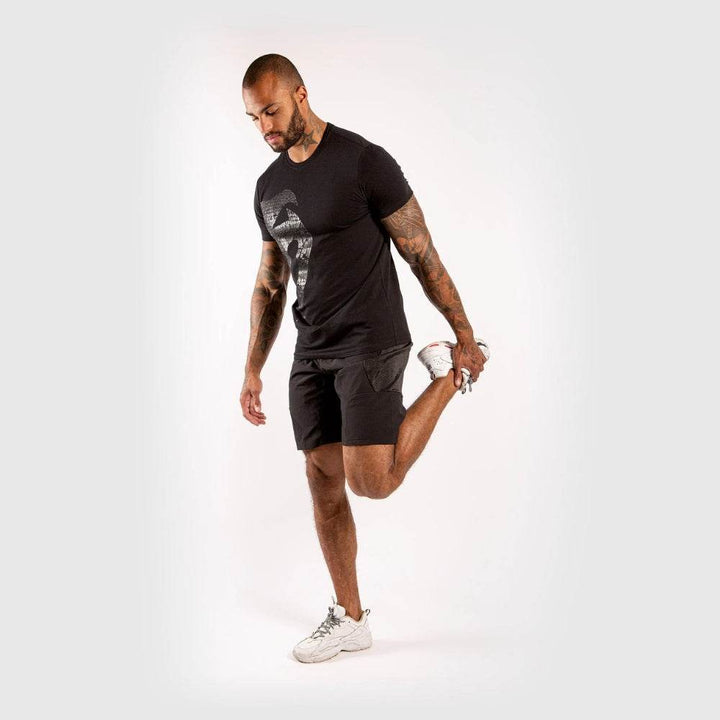 Full-body shot of the man wearing the same outfit stretching his leg backward, in athletic pose.