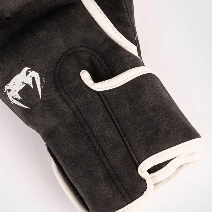 Macro of palm side, highlighting perforations, grip bar and white snake-head icon on soft black surface.