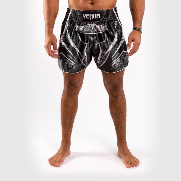 Front view of athlete wearing black-white gladiator-themed Muay Thai shorts with white "VENUM" waistband.
