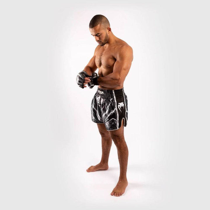 Full body image of athlete wearing the skeleton-themed shorts and MMA gloves.