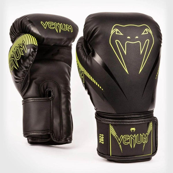 Pair of Venum Impact boxing gloves positioned with palms facing forward, highlighting neon yellow stripes and Venum branding on the thumb.