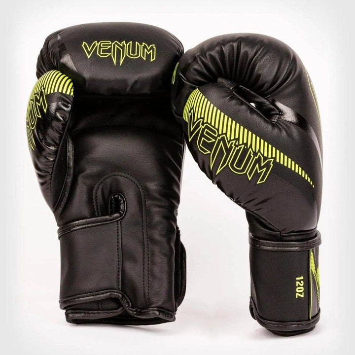 Front and side view of Venum Impact boxing gloves in black with neon yellow accents, showing the Venum logo and fanged snake design.