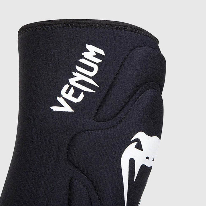 Close-up of the Venum branding in white and detailed stitching on the padded black surface of the knee pad.