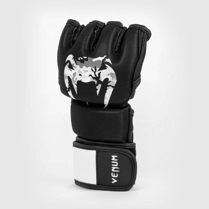 Angled view of a black Venum Legacy MMA glove showcasing the bold white camouflage Venum logo and layered protective padding.
