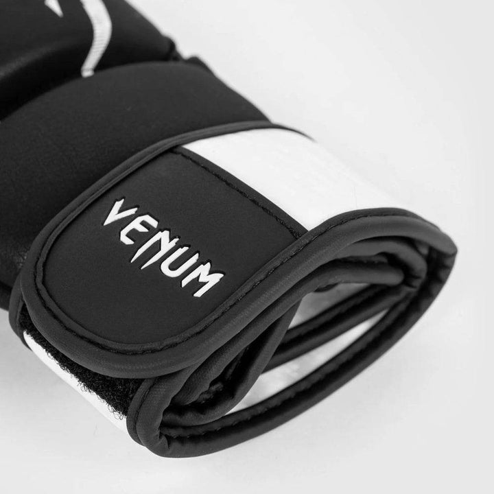 Close-up of the black wrist strap on the Venum Legacy MMA glove, featuring white Venum branding embroidered onto the curved end of the wrap.