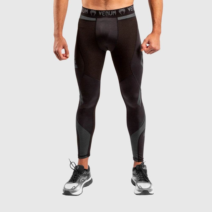 Front view of black Venum compression spats with wide waistband featuring Venum logos, mesh fabric on thighs and shins for breathability.