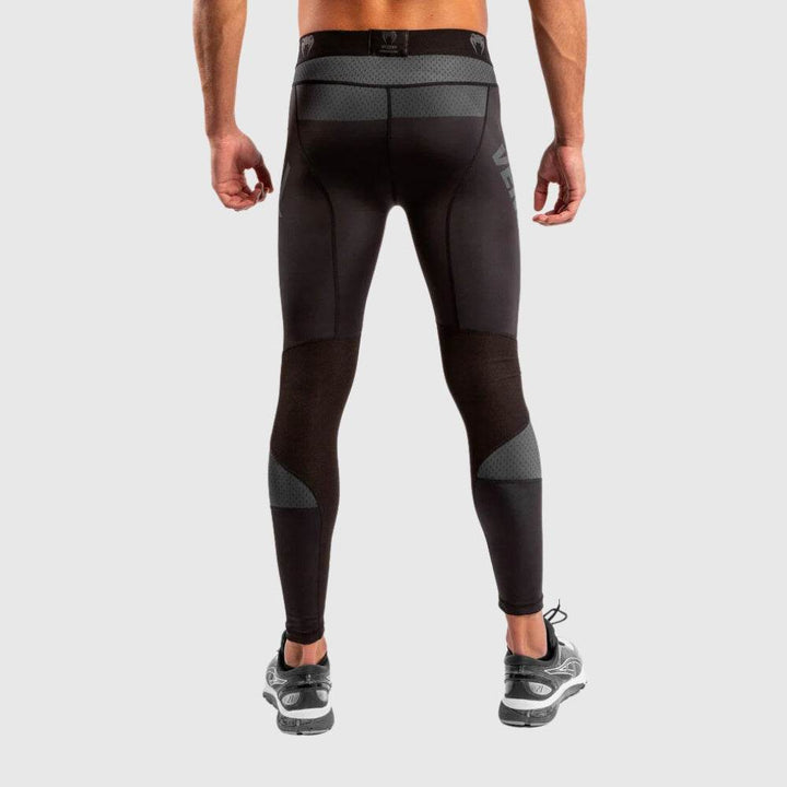 Back view of Venum men’s compression spats showing mesh paneling on calves and waistband details, fitted design contouring to leg shape.