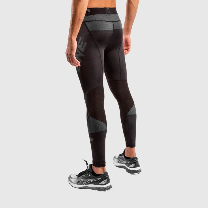 Angled rear view of compression spats showcasing curved seam design, grey mesh inserts, and “ONE” branding on left hamstring area.