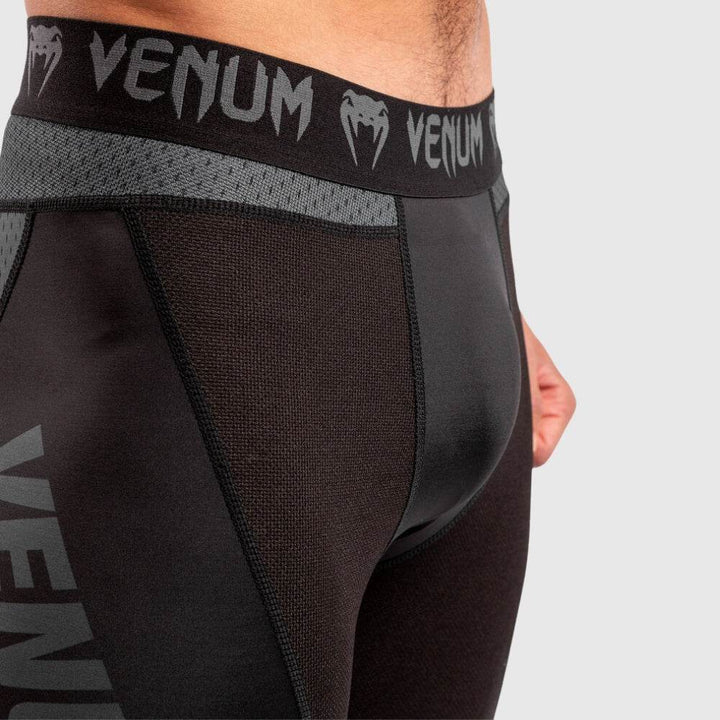 Close-up of black elastic waistband with repeating Venum logos and reinforced stitching on the upper hip area.