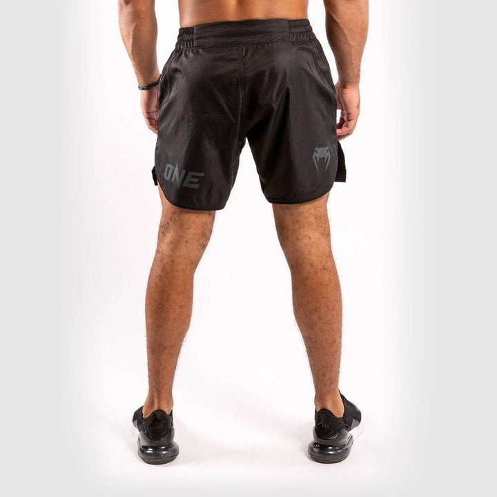 Back view of Venum fight shorts with "ONE" and snakehead logo in matte black on the lower legs, elastic waistband, and rounded hem design.