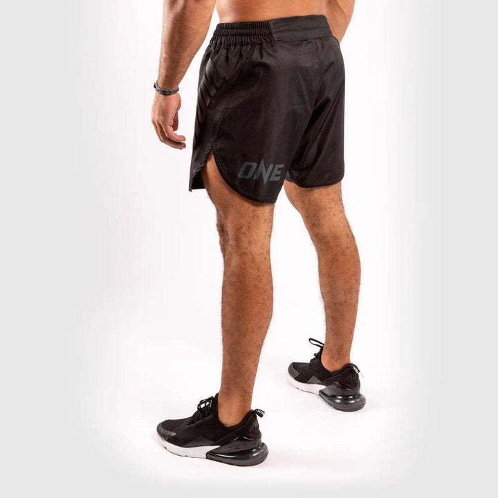 Angled rear view showing the "ONE" logo on the left leg, back curve hem design and lightweight black fabric construction of Venum shorts.