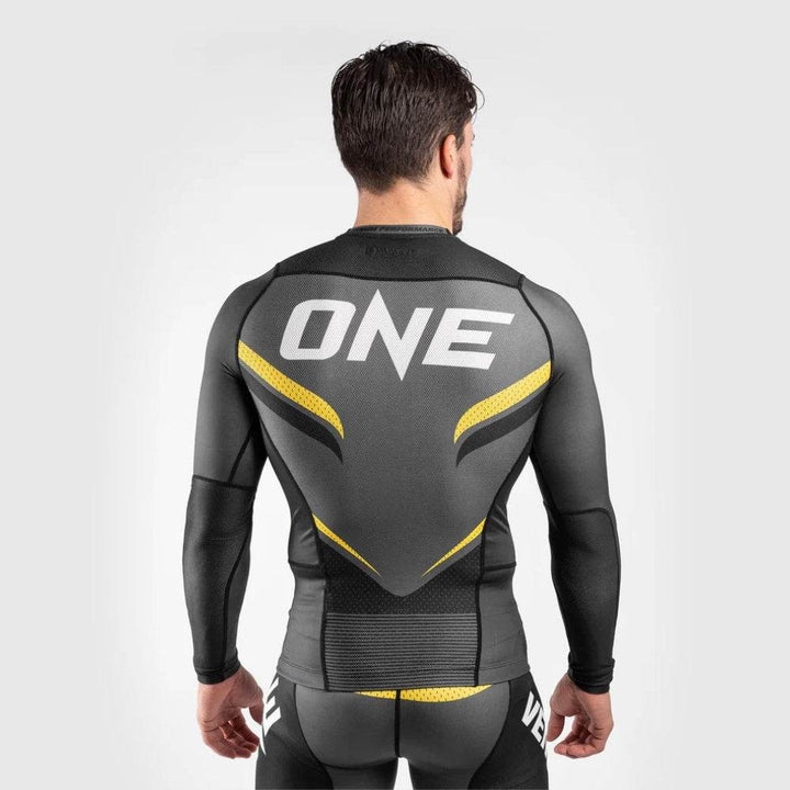 Back of the Venum ONE long-sleeve rash guard with white “ONE” text and yellow snake scale graphics.