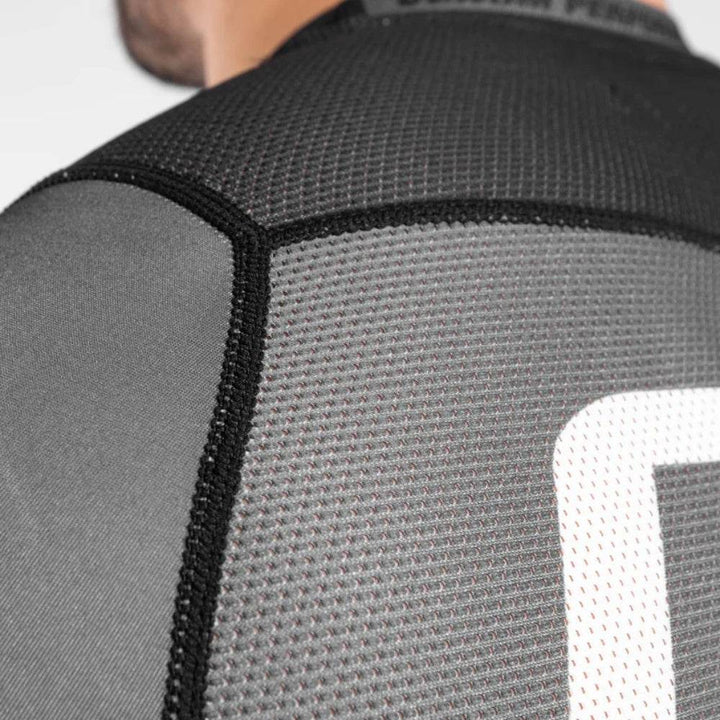 Macro image focusing on the stitching and mesh panel on the back shoulder area of the rash guard.