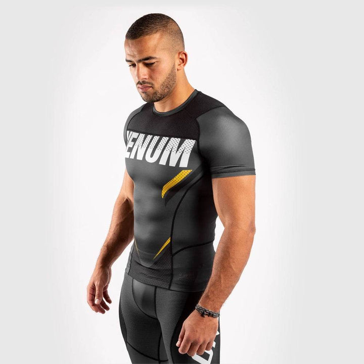 Side angle of Venum rash guard highlighting torso fit and yellow slash detail.