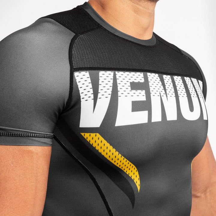 Detailed view of VENUM text with yellow slash on compression fabric. With mesh faric around the neck for heat management.
