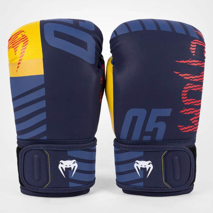 A pair of Venum Sport 05 boxing gloves in navy blue with yellow thumbs and red graphic details, standing upright with the front and side views visible.