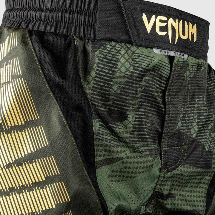 Close-up of waistband with gold Venum logo patch and camo panel beneath.