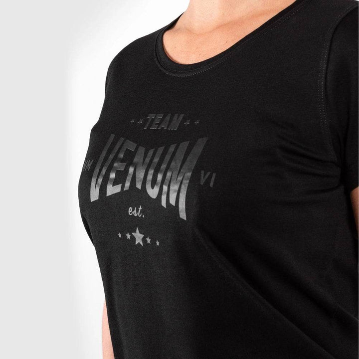 Close-up of the Venum Team logo printed in black on a black t-shirt.