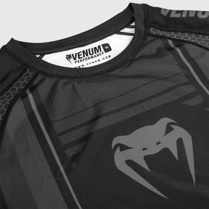 Zoomed-in detail of the collar and chest of the black Venum rash guard, focusing on the fine hexagonal mesh texture and Venum Performance label inside the neckline.