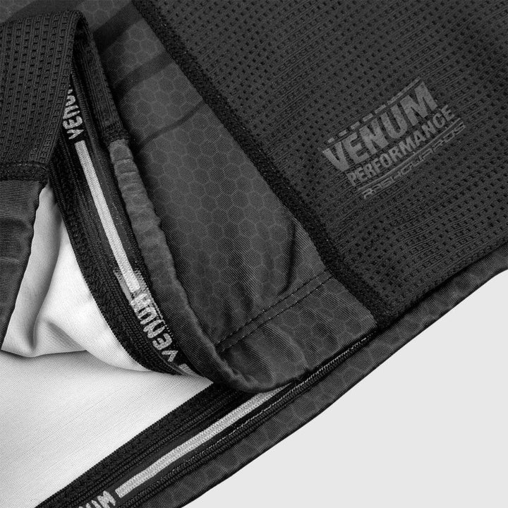 Detailed shot of the inner seam and hem of the rash guard, revealing inner taping and “Venum Performance Rashguards” branding printed in grey on the mesh panel.