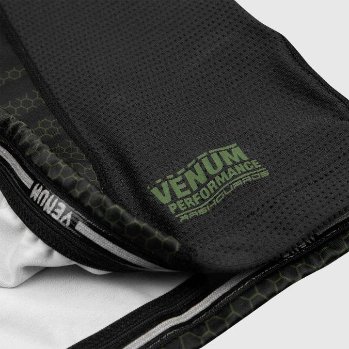 Close-up of the bottom hem revealing interior stitching, elastic grip band, and "VENUM PERFORMANCE RASHGUARDS" branding.