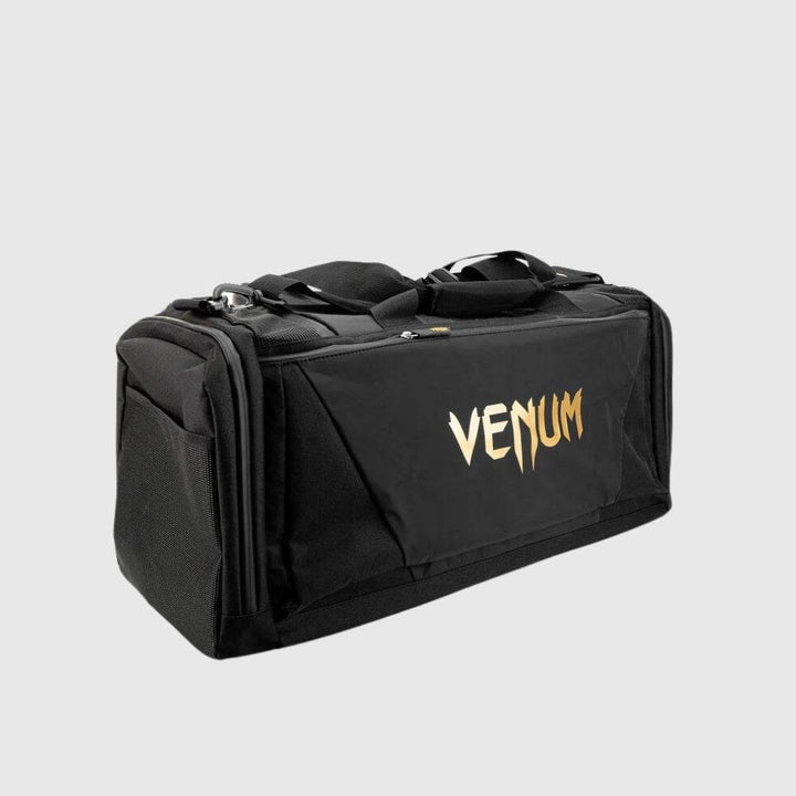 Rear view of the Venum Trainer Lite EVO Sport Bag in black with metallic gold VENUM logo, showing reinforced stitching and side panel structure.