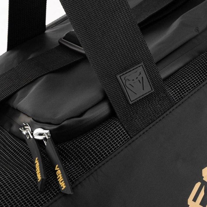 Close-up of the Venum Trainer Lite EVO Sport Bag’s top handle area, showing reinforced stitching, rubber Venum logo patch, mesh ventilation panel, and branded zipper pulls.