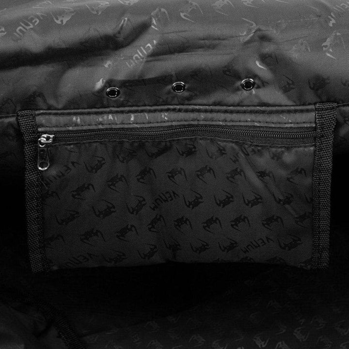 Interior view of the Venum Trainer Lite EVO Sport Bag showing a zippered mesh pocket with all-over Venum logo lining and interior ventilation eyelets.