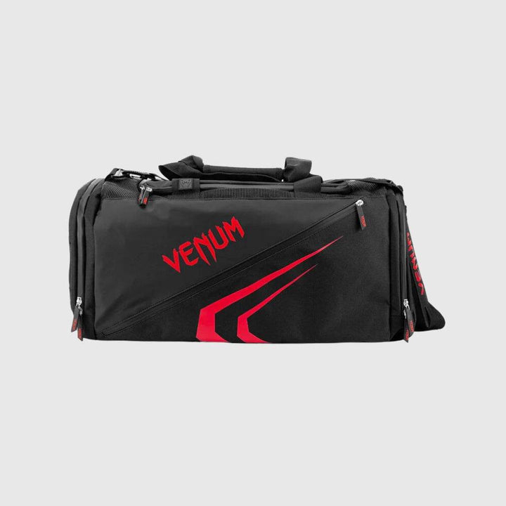 Front view of the Venum Trainer Lite EVO Sport Bag in black with bold red VENUM logo and angular red graphic design, featuring multiple zippered compartments and sturdy handles.
