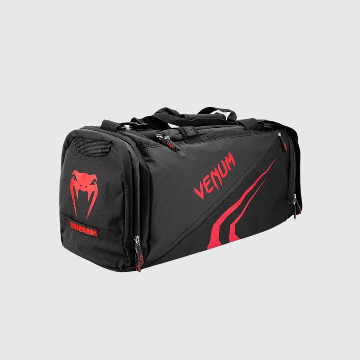 Three-quarter view of the Venum Trainer Lite EVO Sport Bag in black and red, featuring a red Venum snake logo on the side pocket, bold branding, and multi-compartment design.