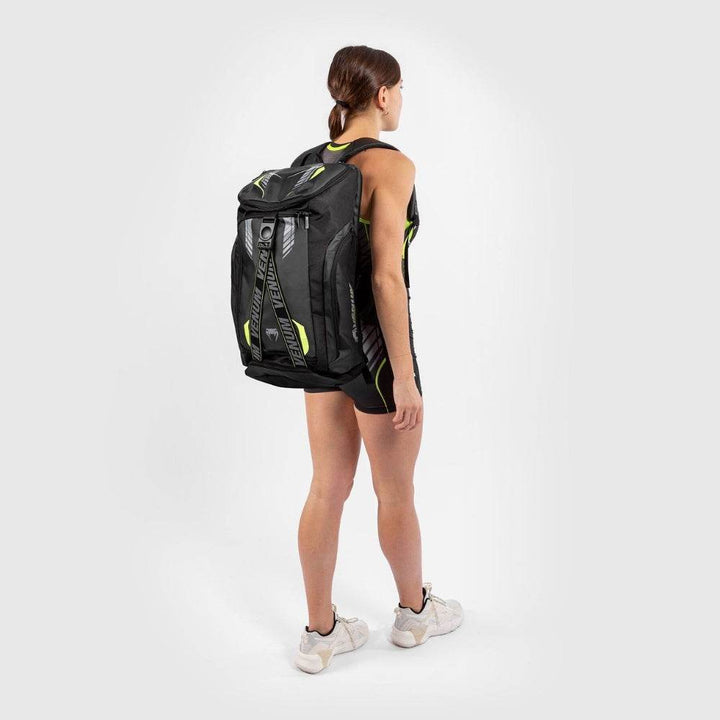 Woman wearing the Venum backpack, showcasing its full size and athletic fit against a training outfit.