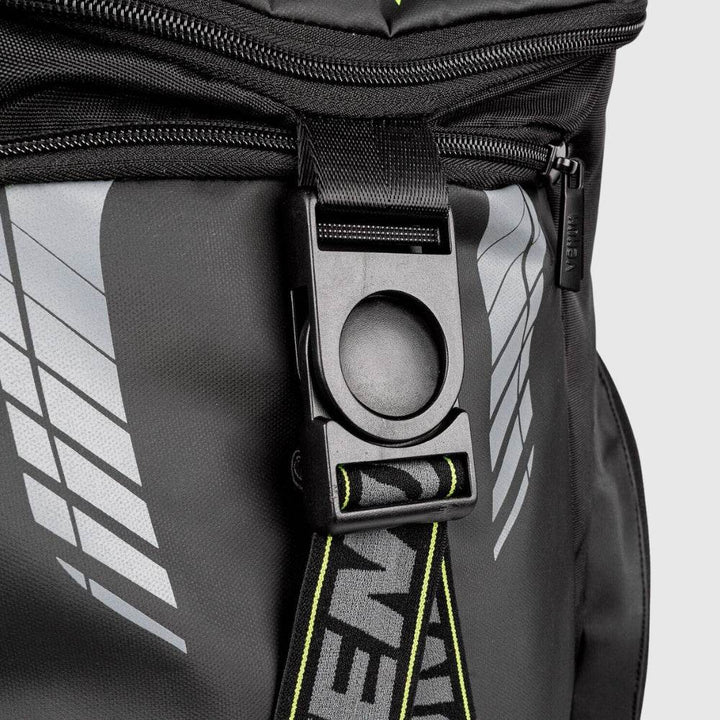 Close-up of the Venum backpack’s front locking buckle with matte black finish, attached to branded strap and surrounded by reflective graphic elements.
