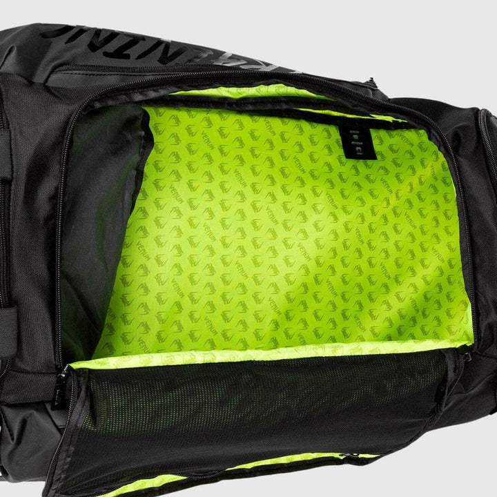 Open view of the Venum backpack’s main storage compartment with neon green interior and mesh zippered flap for securing contents.