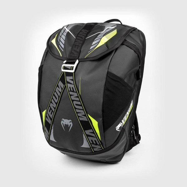 Black Venum sports backpack with neon yellow accents and bold VENUM branding, featuring a top flap with adjustable strap, side mesh pockets, and a sleek, angular design.