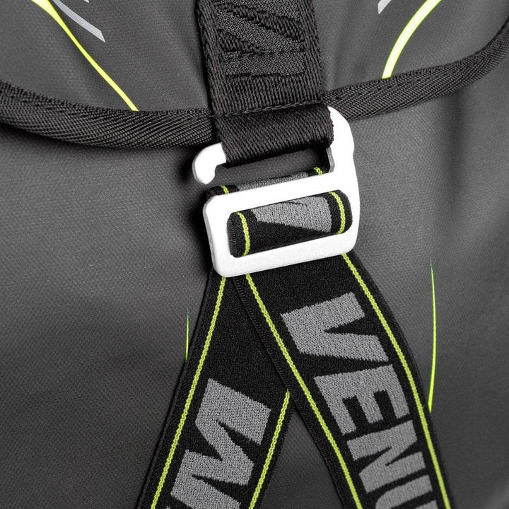 Close-up of the Venum backpack’s front strap and buckle, showing durable black webbing with VENUM branding and neon green stitching detail.