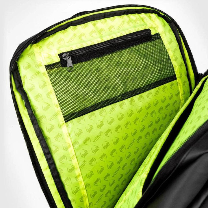 Interior view of the Venum backpack showcasing bright neon green lining with Venum logos and a zippered mesh pocket for organized storage.