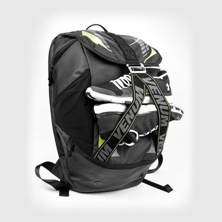 Venum sports backpack packed with athletic gear including boxing gloves and training shoes, secured by branded front straps with bold VENUM lettering.